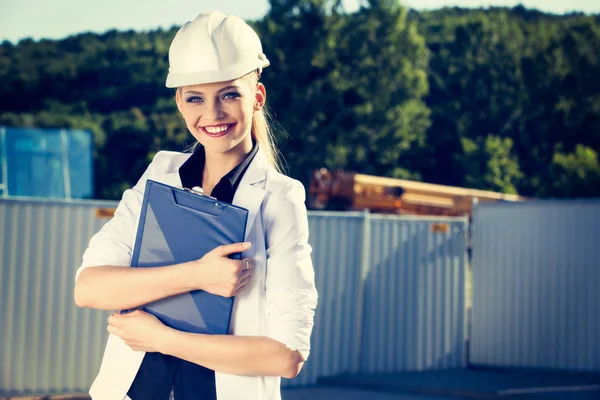 Kvinnlig ingenjör i hjälmen framför byggarbetsplats — Stockfoto
