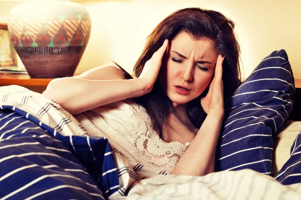 Young sick woman lying on her bed in bedroom — Stock Photo, Image