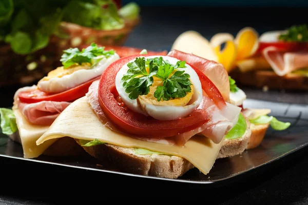 Sanduíche delicioso com presunto prosciutto, queijo, tomate e ovo — Fotografia de Stock