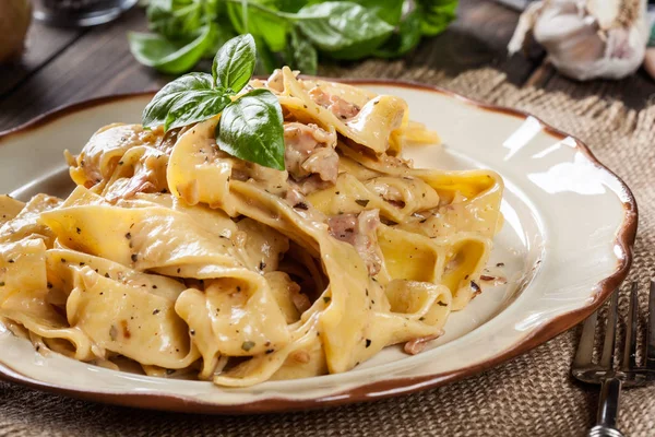 Massa de pappardelle com molho de queijo e prosciutto em um prato — Fotografia de Stock