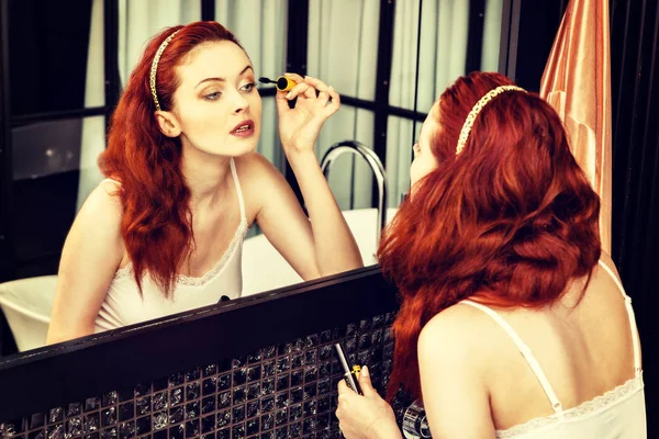 Closeup of an red-haired woman applying mascara in mirror — Stock Photo, Image