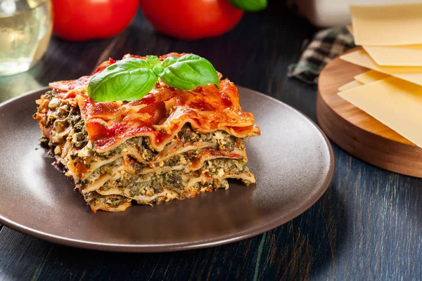 Pezzo di gustose lasagne calde con spinaci su un piatto — Foto Stock