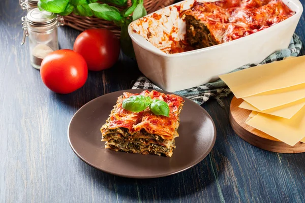 Trozo de sabrosa lasaña caliente con espinacas en un plato — Foto de Stock