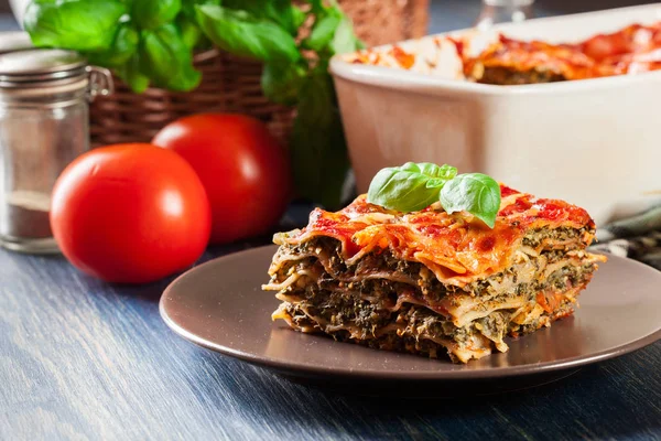 Trozo de sabrosa lasaña caliente con espinacas en un plato — Foto de Stock