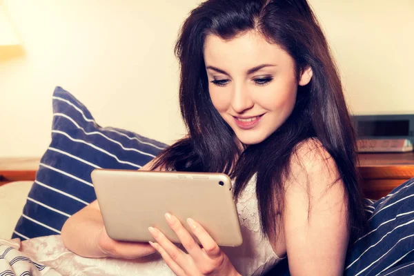 Young woman lying on the bed and using tablet — Stock Photo, Image