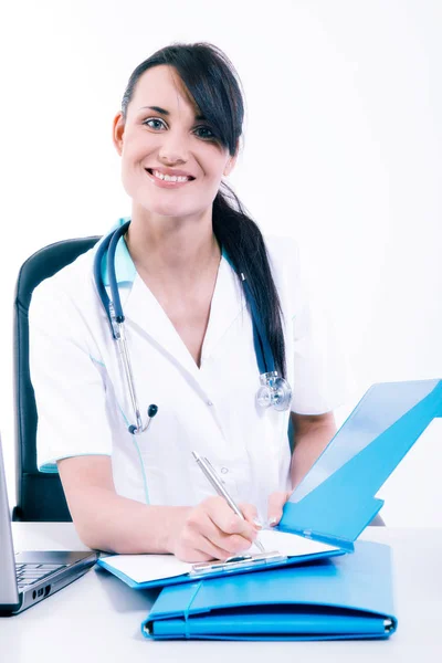 Ärztin sitzt am Schreibtisch und lächelt in die Kamera — Stockfoto