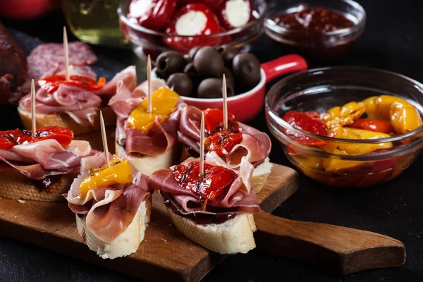 Spanische Tapas mit Scheiben Marmeladenserrano und gegrilltem Pfeffer. auch Oliven, Salami, eingelegte Zwiebeln und Paprika gefüllt mit Käse — Stockfoto