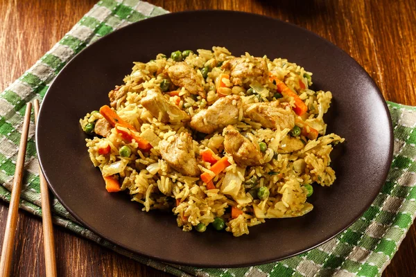 Жареный рис наси горенг с курицей и овощами на тарелке — стоковое фото
