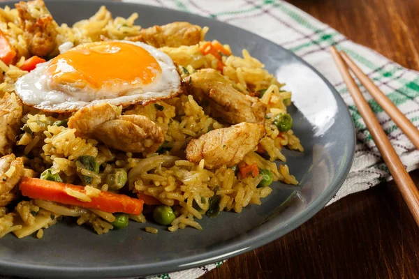 Stekt ris nasi goreng med kyckling ägg och grönsaker på en tallrik. — Stockfoto