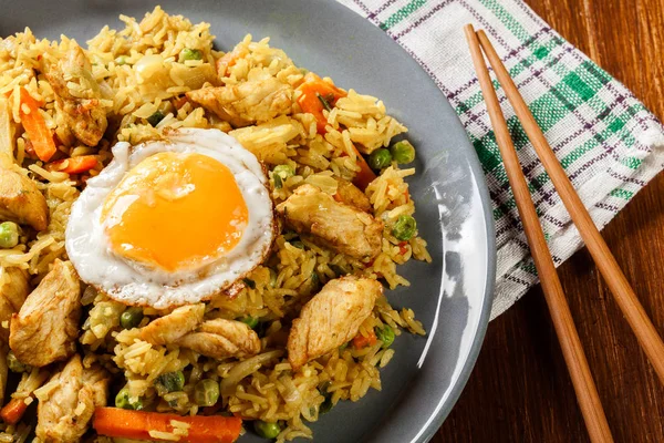 Stekt ris nasi goreng med kyckling ägg och grönsaker på en plat — Stockfoto