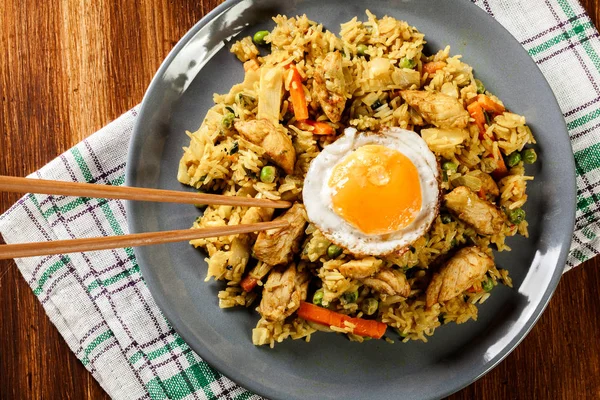 Stekt ris nasi goreng med kyckling ägg och grönsaker på en plat — Stockfoto