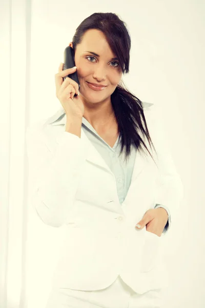 Attractive young woman having negotiations by phone in office — Stock Photo, Image