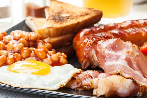 Compleet Engels ontbijt met spek, worst, ei, gebakken bonen en jus d'orange — Stockfoto
