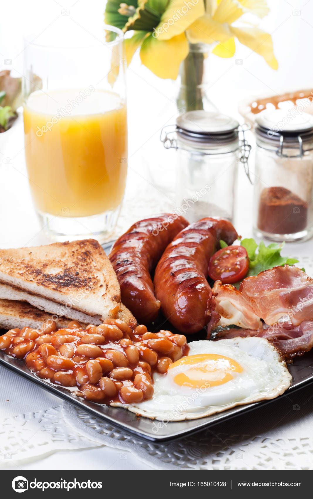 Full English breakfast with bacon, sausage, egg, baked beans and orange