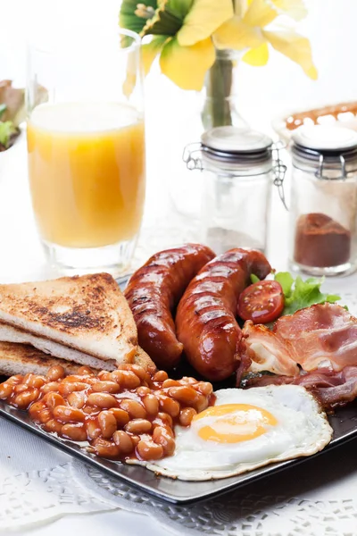 与培根、 香肠、 鸡蛋、 烤的豆子和橙汁的全套英式早餐。 — 图库照片