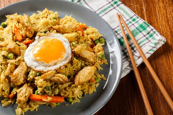 Stekt ris nasi goreng med kyckling ägg och grönsaker på en plat — Stockfoto