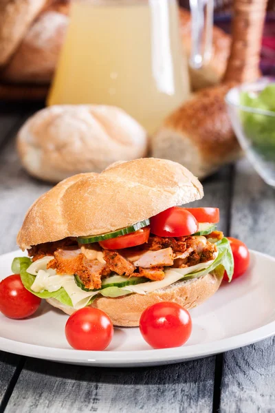 Fried chicken meat with cheese and vegetables in bun — Stock Photo, Image