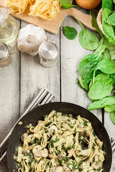 Tagliatelle met spinazie en paddestoelen op een pan pasta. — Stockfoto