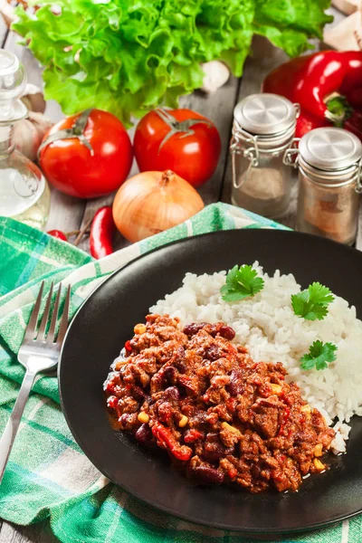 Hot chili con carne with ground beef, beans, tomatoes and corn served with rice — Stock Photo, Image