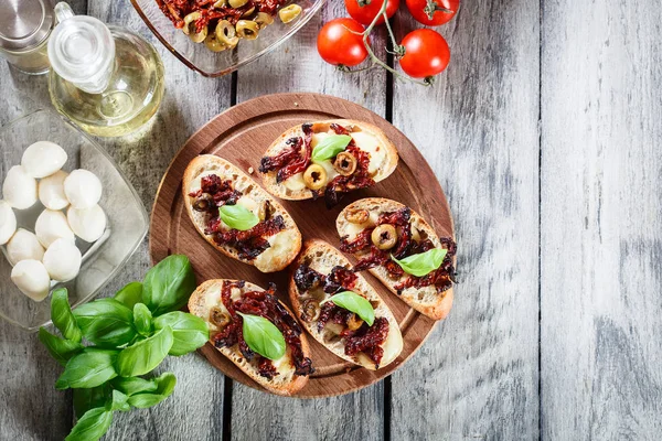 Vorspeise Bruschetta mit sonnengetrockneten Tomaten, Oliven und Mozarel — Stockfoto