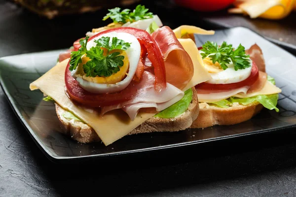 Prosciutto jambonu, peynir, domates ve yumurta ile lezzetli sandviç — Stok fotoğraf