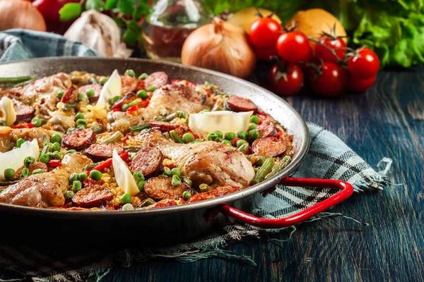 Traditional paella with chicken legs, sausage chorizo and vegetables served in paellera — Stock Photo, Image