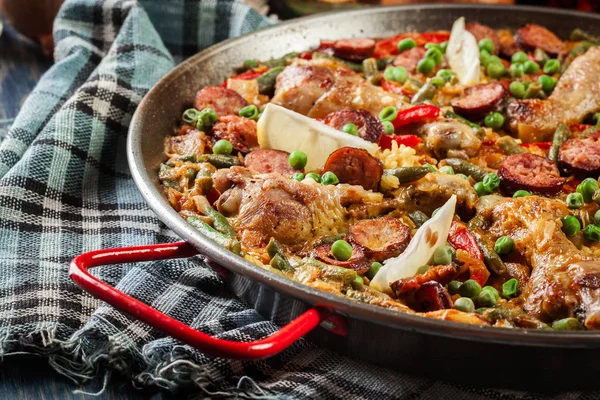 V paellera podává tradiční paella s kuřecích stehen, chorizo klobásou a zeleninou — Stock fotografie