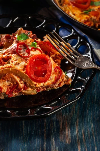 Porção de frittata com ovos, chouriço de linguiça, pimenta vermelha, pimenta verde, tomate, queijo e pimenta em um prato na mesa de madeira . — Fotografia de Stock