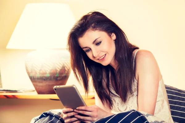 Genç kadın yatakta yatıyordu ve tablet kullanma — Stok fotoğraf