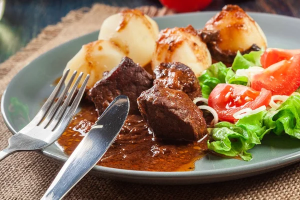 Fläsk köttgryta serveras med potatis och grönsakssallad — Stockfoto