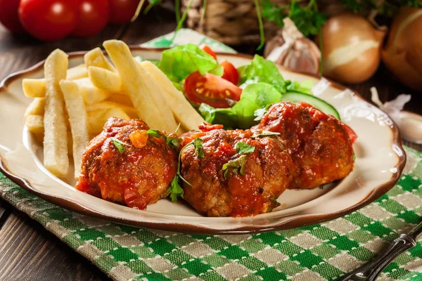 Roasted meatballs in tomato sauce with french fries and salad — Stock Photo, Image