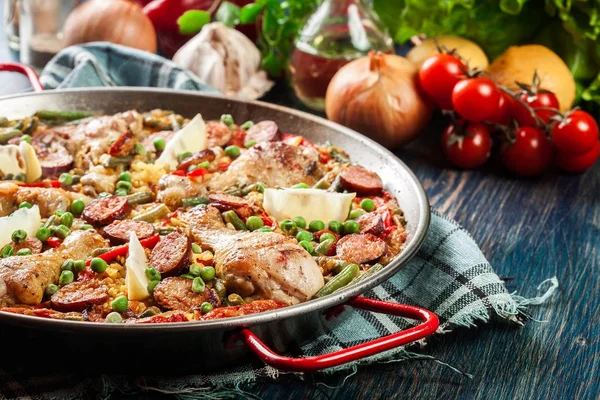 Paella traditionnelle avec cuisses de poulet, chorizo aux saucisses et légumes servis en paellera — Photo