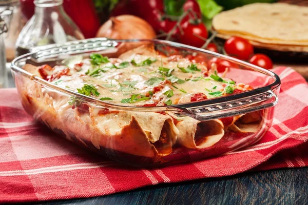 Enchiladas messicani tradizionali con carne di pollo, salsa di pomodoro piccante e formaggio in piatto resistente al calore — Foto Stock