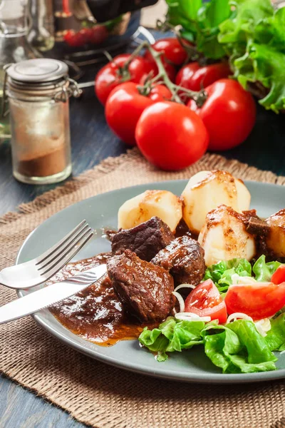 Guisado de carne de porco servido com batatas e salada de legumes — Fotografia de Stock