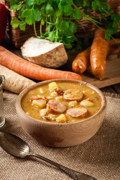 Дерев'яна миска з горіхового супу з ковбасою та картоплею — стокове фото