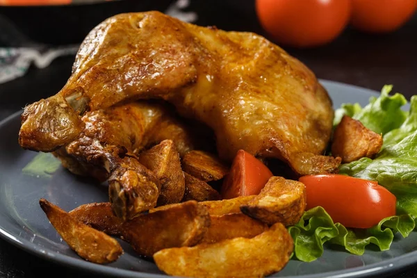 Roasted chicken legs with potato wedges and tomatoes — Stock Photo, Image