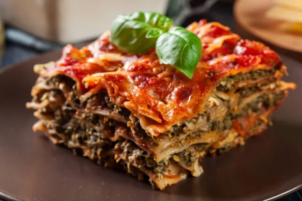 Bit av välsmakande varm lasagne med spenat på en tallrik — Stockfoto