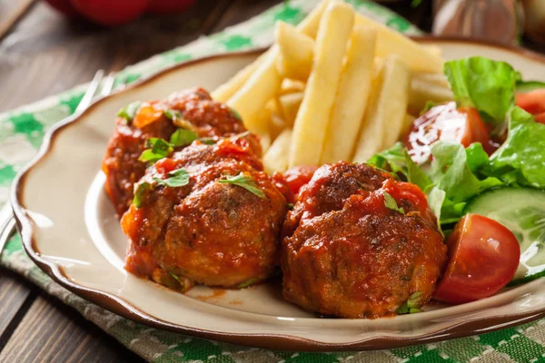 Gebratene Hackbällchen in Tomatensauce mit Pommes und Salat — Stockfoto