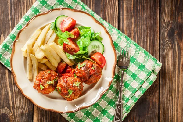 Roasted meatballs in tomato sauce with french fries and salad — Stock Photo, Image