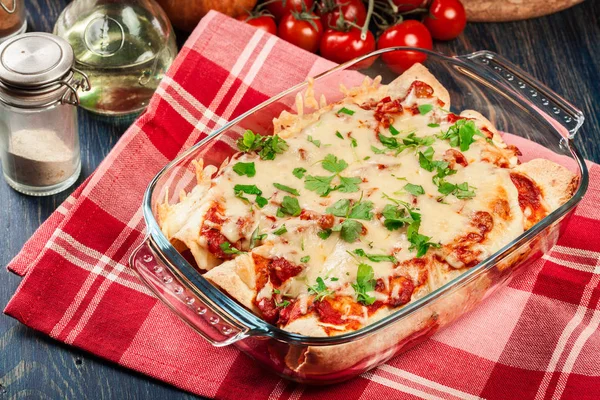 Enchiladas mexicanas tradicionales con carne de pollo, salsa de tomate picante y queso en plato resistente al calor —  Fotos de Stock