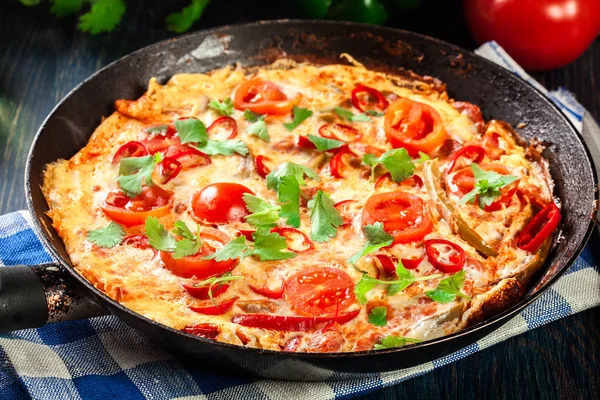 Yumurta, chorizo sosis, kırmızı biber, yeşil biber, domates, peynir ve biber ahşap masa üzerinde bir tavada Frittata yapılmış — Stok fotoğraf