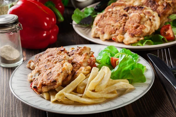 Medallones de pollo con pimientos rojos servidos con papas fritas —  Fotos de Stock