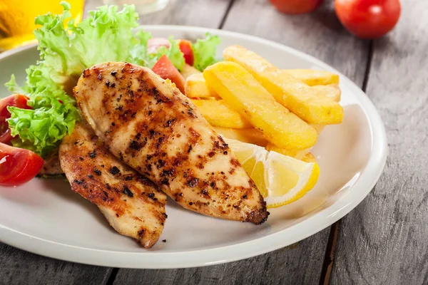 Petti di pollo alla griglia serviti con patatine fritte e insalata fresca — Foto Stock