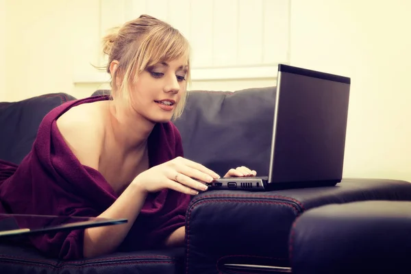 Giovane donna con i capelli biondi che lavora sul suo computer portatile a casa — Foto Stock