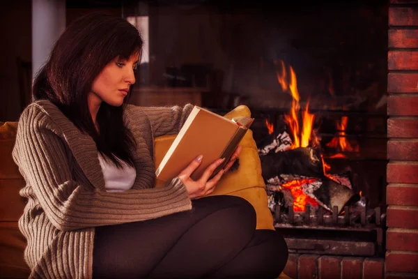 Jeune femme lisant un livre près de la cheminée — Photo