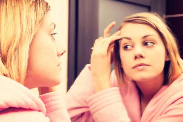 Blond žena očistit její tvář make-up. Dívka, která nosí v županu — Stock fotografie