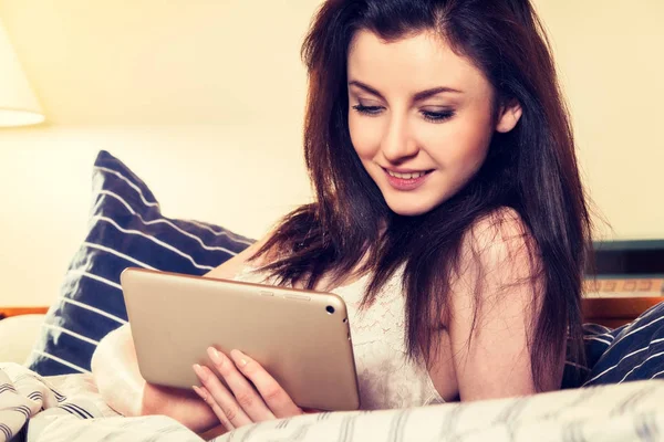 Jonge vrouw liggend op het bed en het gebruik van Tablet PC — Stockfoto