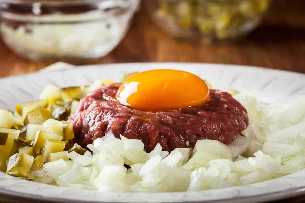 Steak tartare with egg yolk, onions and pickles — Stock Photo, Image