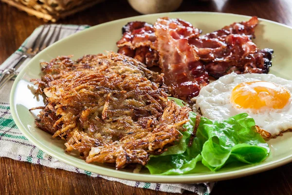 Hash browns. Aardappelpannenkoekjes met krokant gebakken bacon en gebakken ei — Stockfoto