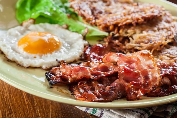 Hash browns. Aardappelpannenkoekjes met krokant gebakken bacon en gebakken ei — Stockfoto